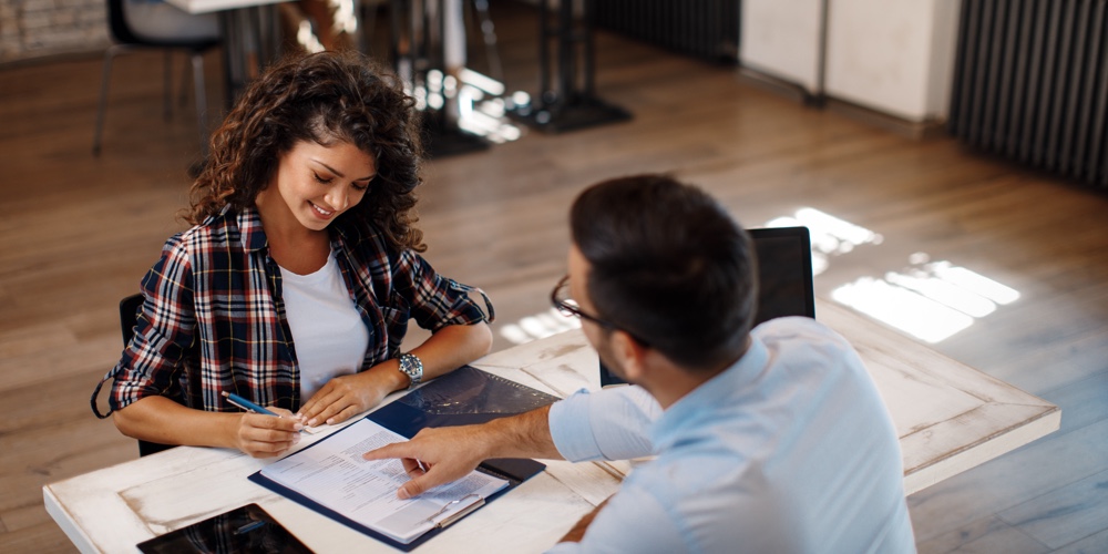 Young woman signing contract with manager