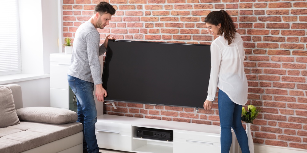 Smiling Young Couple Carrying New Television At Home