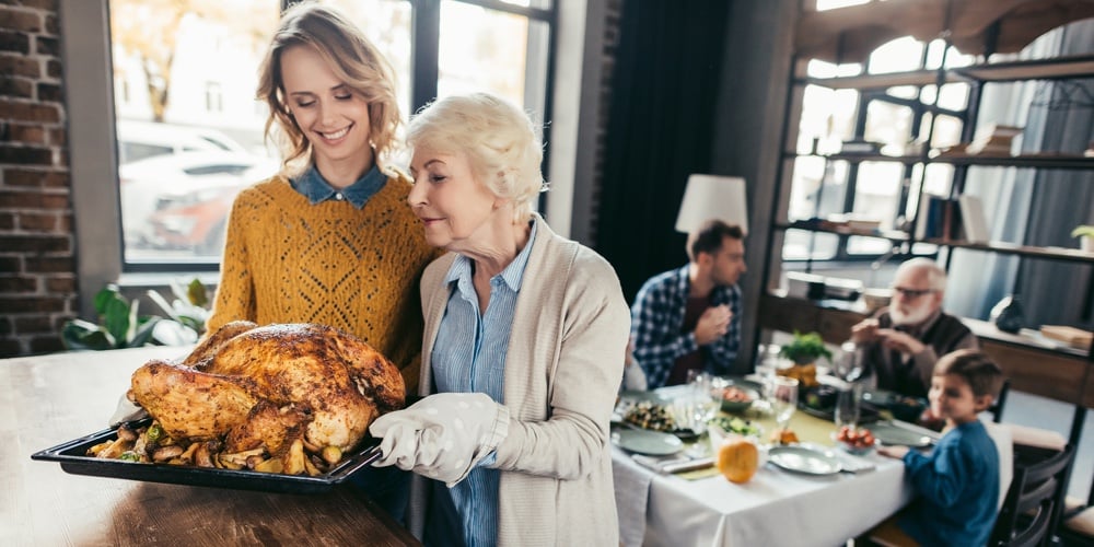senior mother and daughter with thanksgiving turkey for family dinner at home