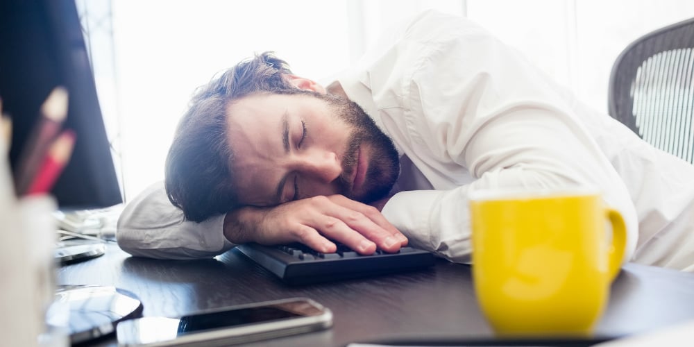 bigstock-A-man-sleeping-on-his-desk-in-135676718