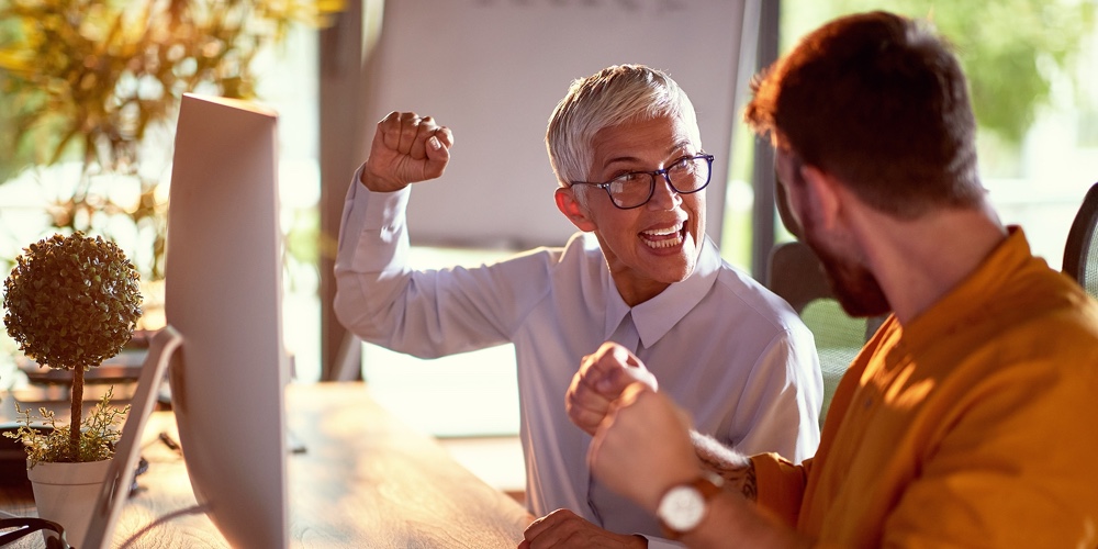 A young businessman and elderly female colleague are yelling and celebrating a done job the are work