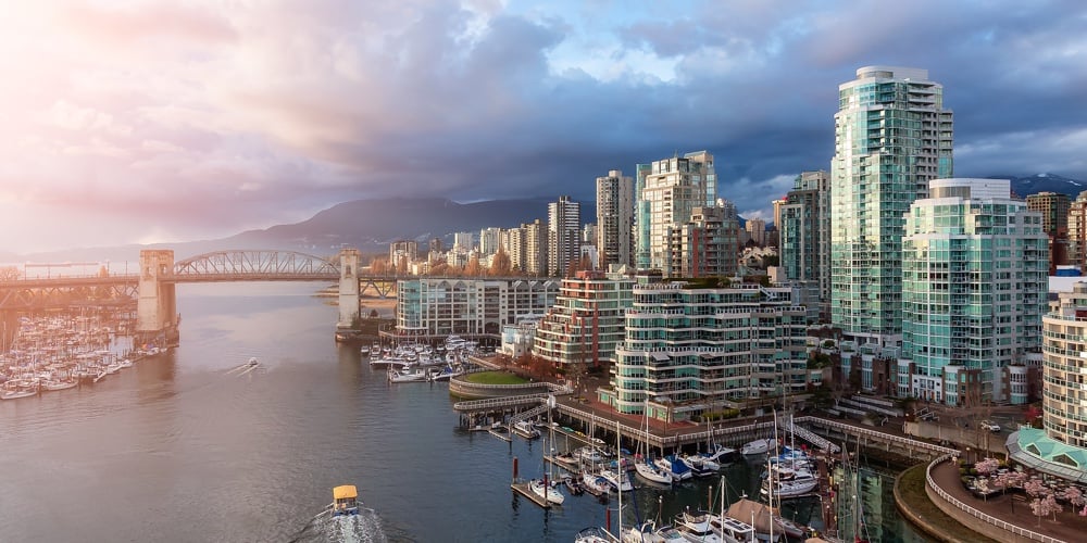 Aerial View Of Granville Island In False Creek With Modern City Skyline And Mountains In Background.