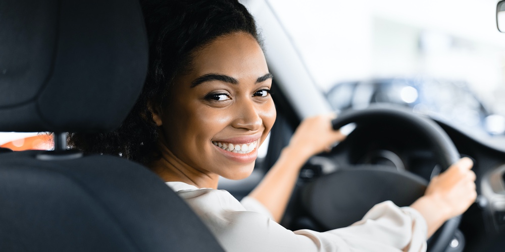 Afro Woman Driver Buying New Car Doing Test Drive Choosing New Auto In Dealership Store. Selective F