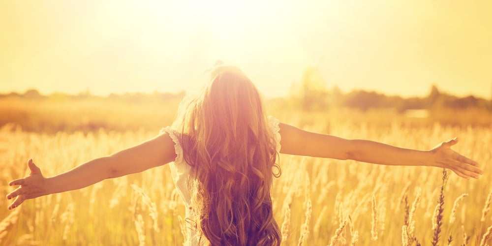 Autumn Girl enjoying nature on the field. Beauty Girl Outdoors raising hands in sunlight rays. Beaut