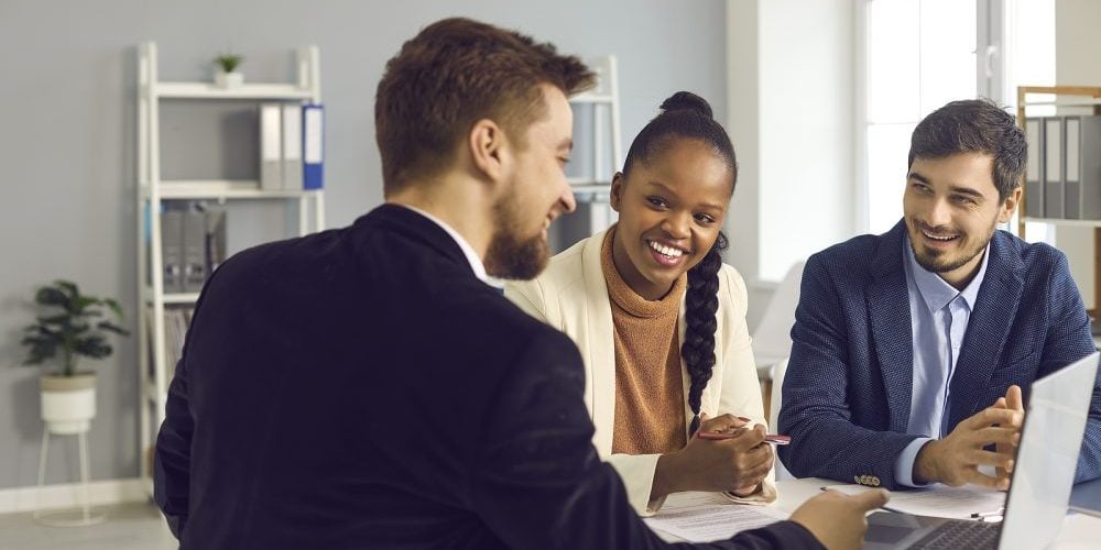 Bank Manager In The Office Consults A Caucasian Man And His Afri