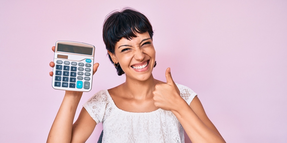 Beautiful brunettte woman showing calculator device smiling happy and positive