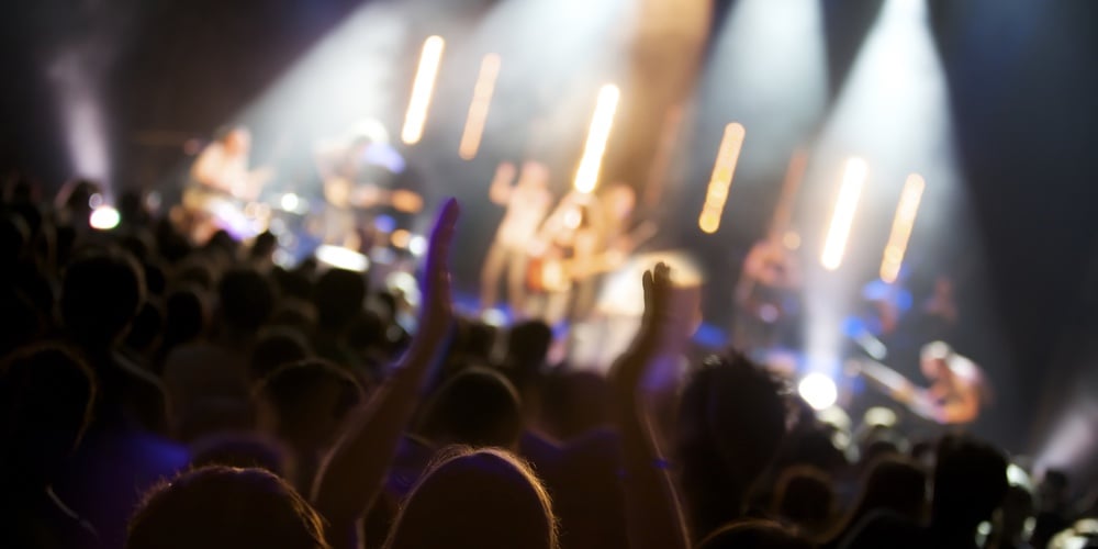 Big crowd of fans listening to live concert of pop band on stage
