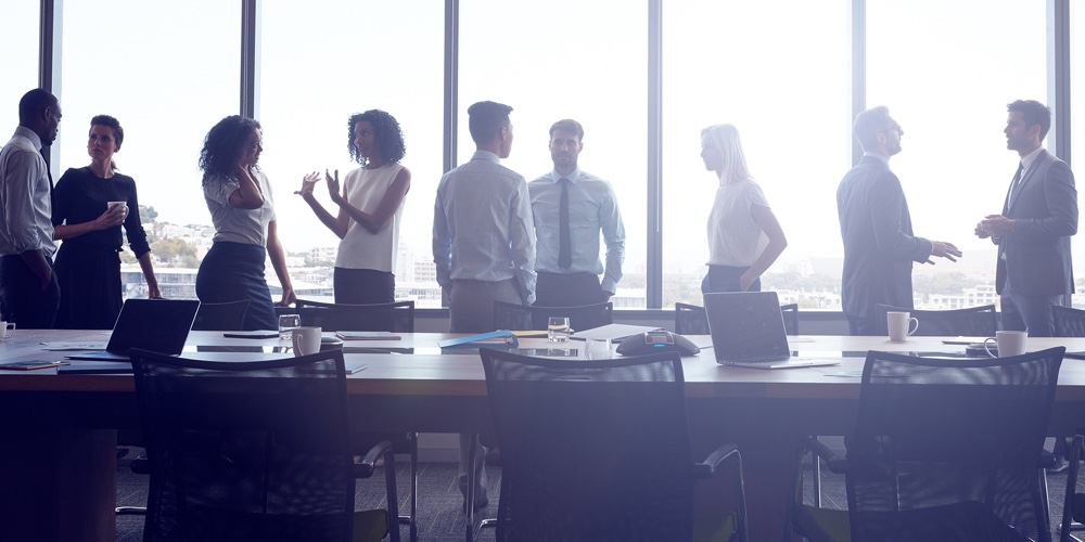 Businesspeople Stand And Chat Before Meeting In Boardroom