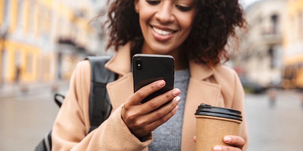 Cheerful young african woman wearing coat walking outdoors