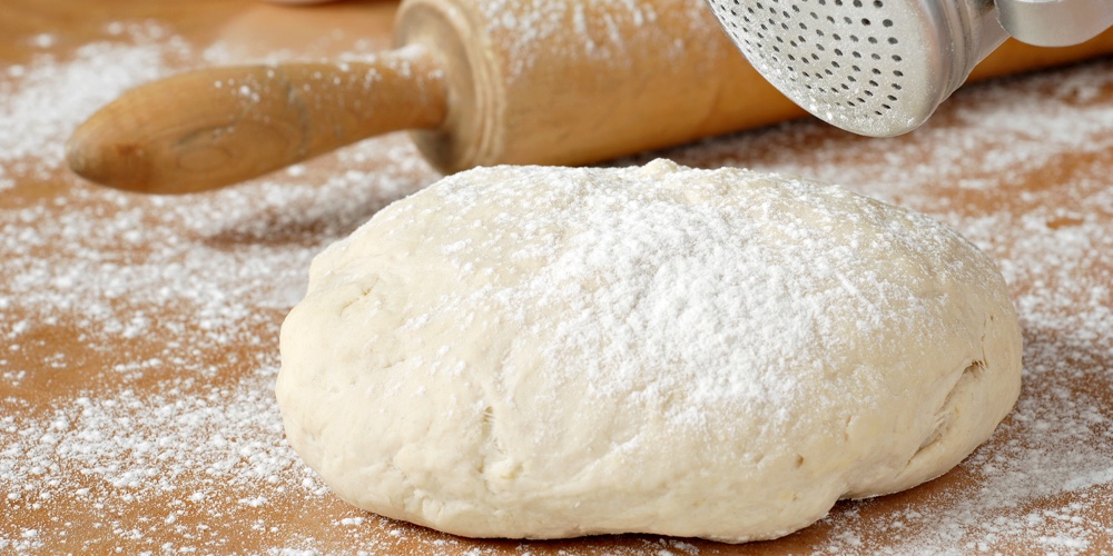 Classic wooden rolling pin with freshly prepared dough and retro flour shaker.  Shallow dof.  Select