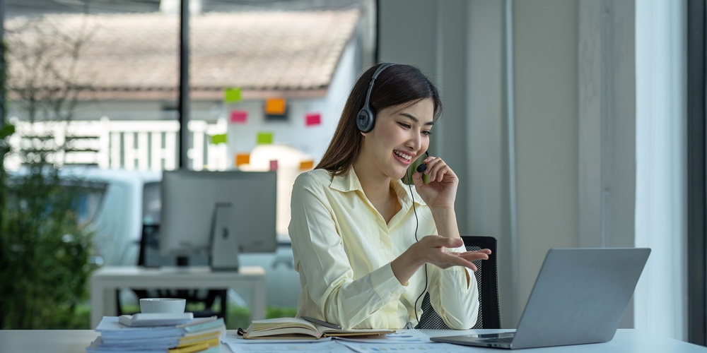 Close Up Call Center Operator In Wireless Headset Talking With Customer