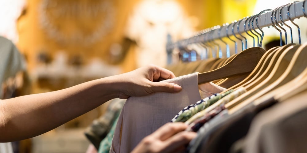 Close Up Of Woman Hand Choosing Thrift Young And Discount T-shirt Clothes In Store