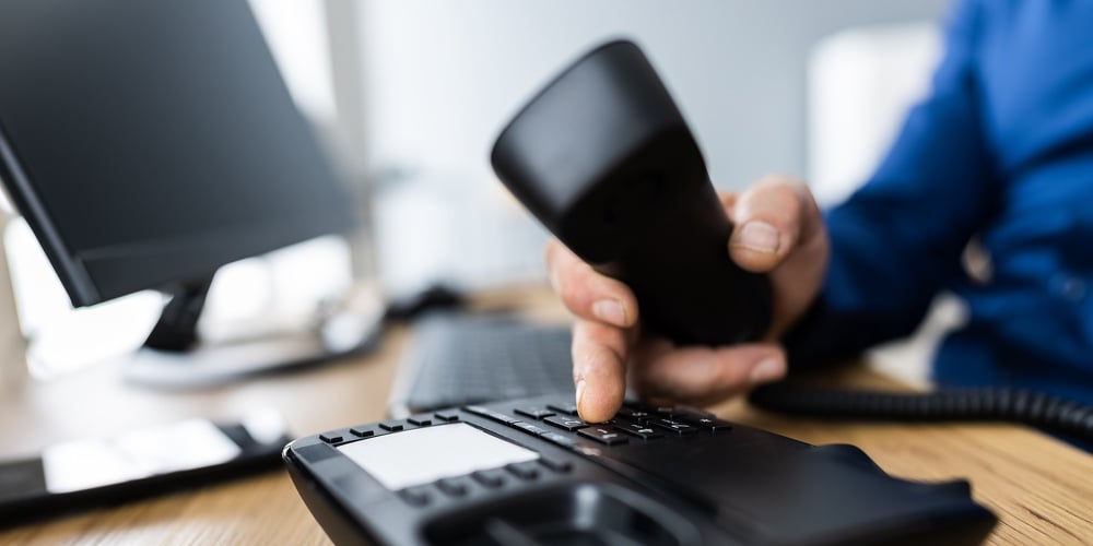 Close-up Of A Businessman’s Hand Dialing Telephone Number To Make Phone Call In Office
