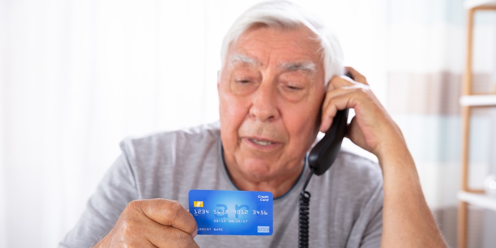 Close-up Of A Senior Man With Credit Card Using Landline Phone
