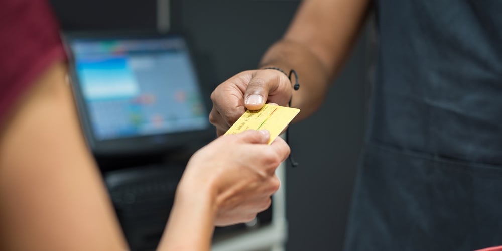 Close up of customer hand giving credit card to cashier at checkout. Woman using credit card to pay