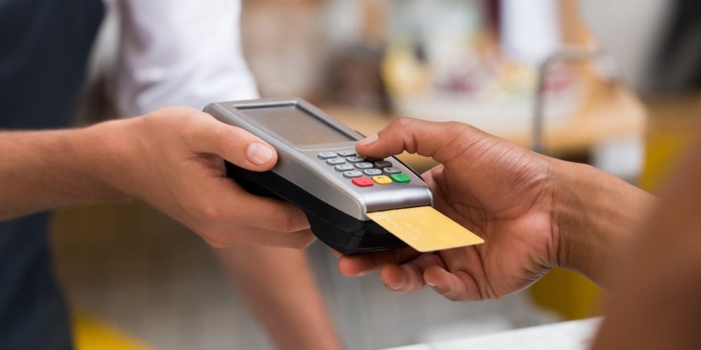 Close up of hand using credit card swiping machine to pay. Hand with creditcard swipe through termin