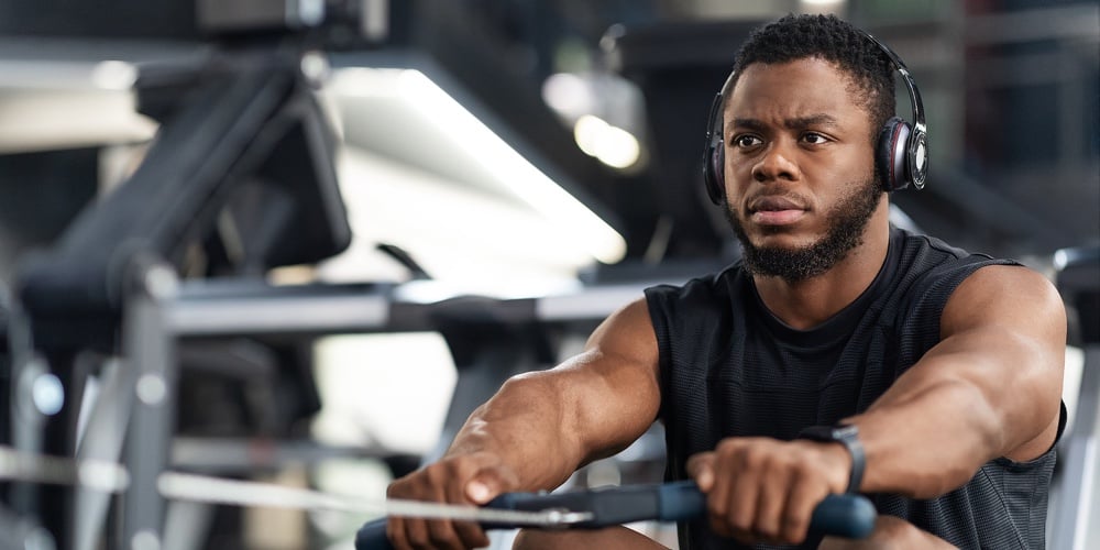 Closeup Of Handsome African American Sportsman Training Body On Modern Rowing Exerciser In Gym