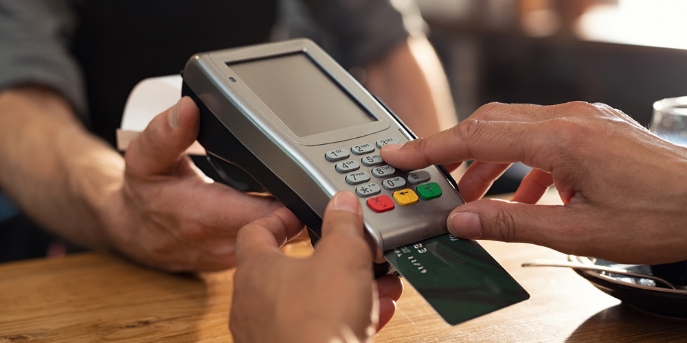 Closeup of hand using credit card swiping machine to pay. Female hand with credit card paying throug