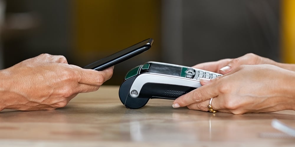 Closeup of woman hand paying a bill through smartphone using NFC technology. Closeup of hand holding