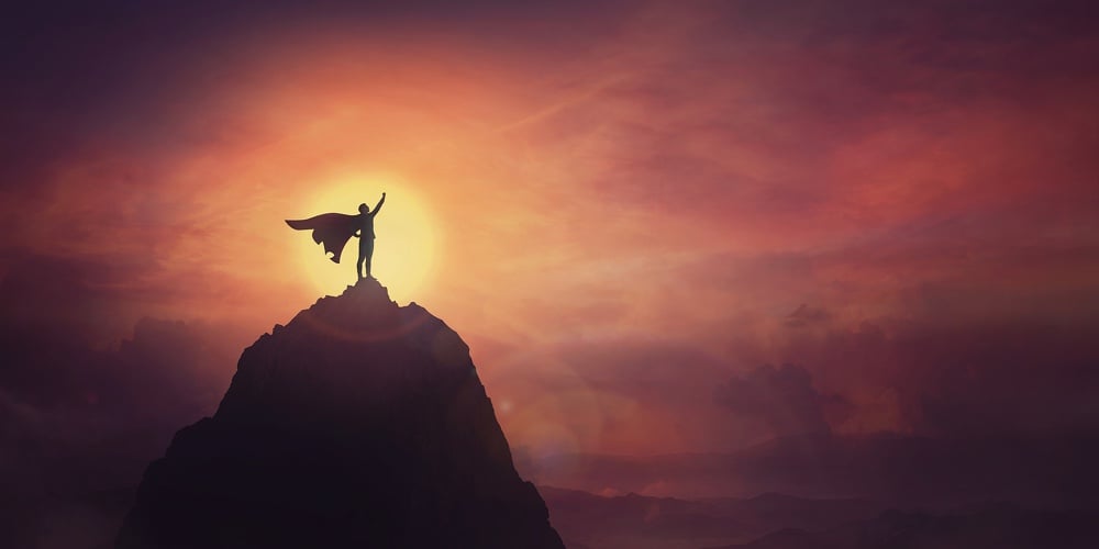 Conceptual Sunset Scene, Superhero With Cape Standing Brave On Top Of A Mountain Looks Determined At