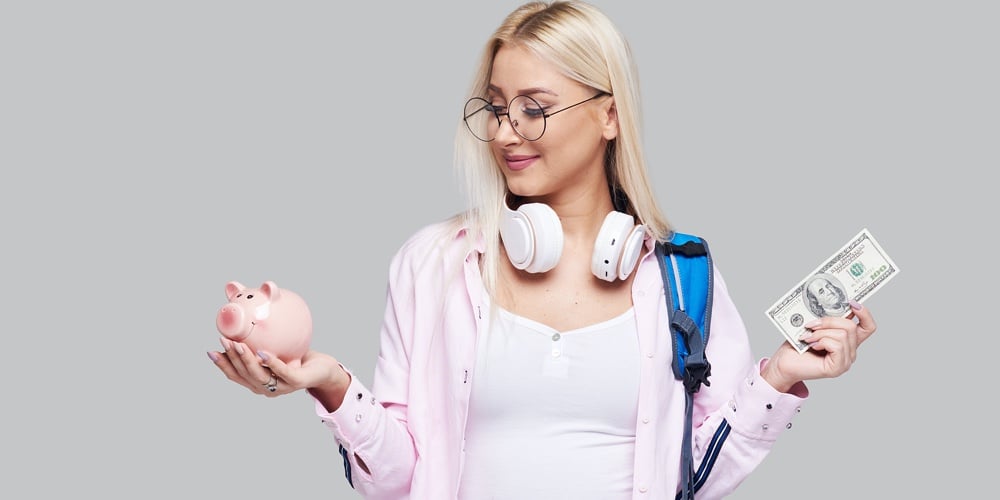 Cost Of College Education. Portrait Of A Happy Female Student With Piggy Bank And Cash Money In Hand