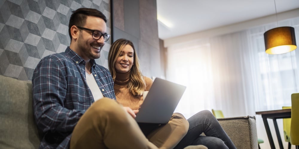 Couple Using Laptop In Living Room At Home