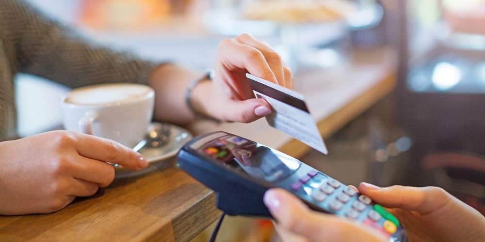 Close up shot of a woman passing a payment credit card to the seller. Woman hand giving credit card
