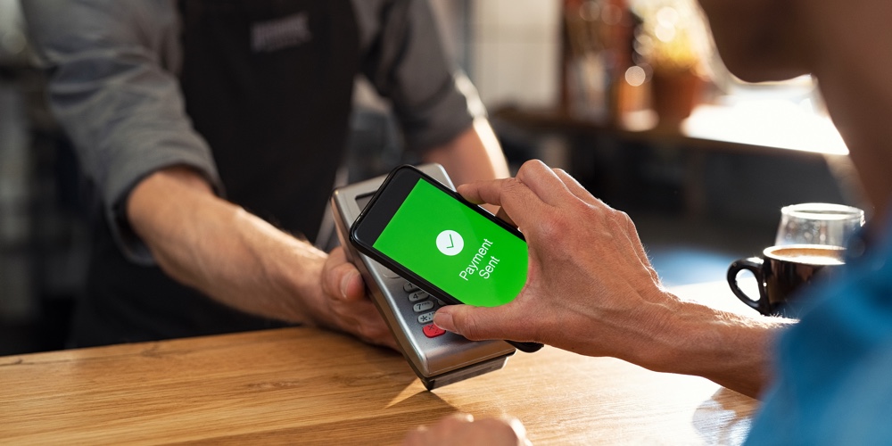 Customer paying bill through smartphone using NFC technology. Closeup of hand making payment through