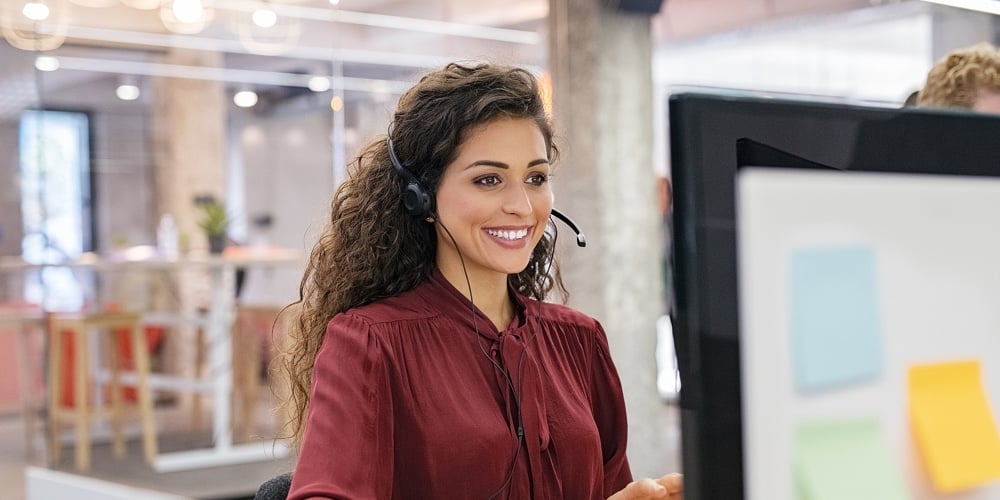 Customer support phone operator working at computer. Happy call center agent working on support hotl