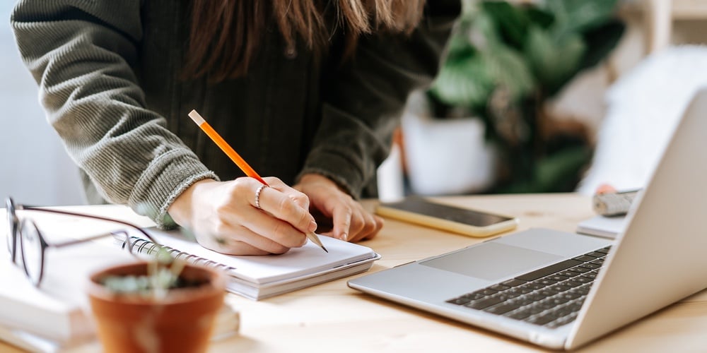 Distance Learning Online Education And Work. Business Woman With Plants Writes In Notebook. Cropped