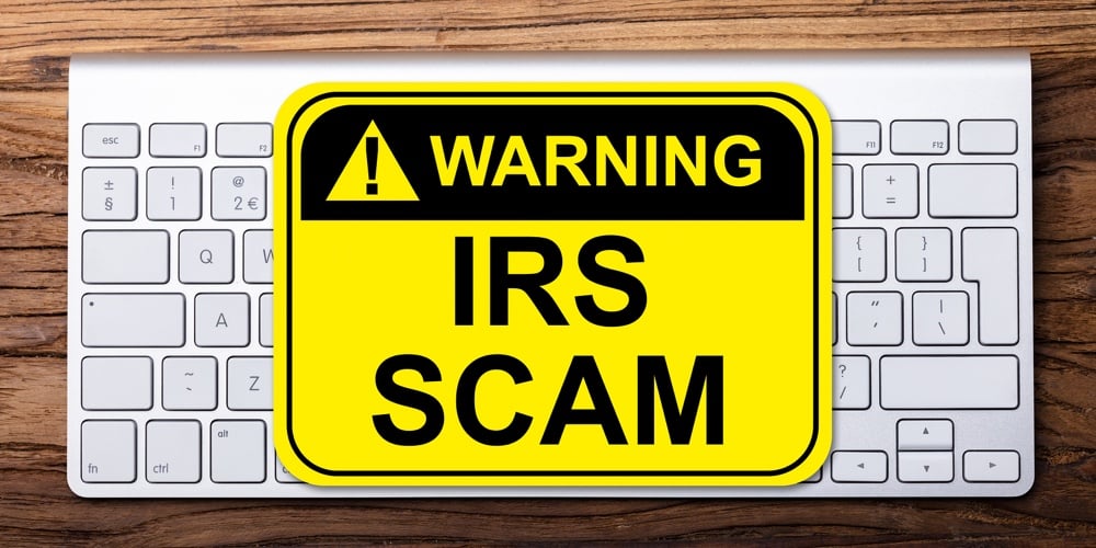 Elevated View Of Irs Scam Warning Sign On Keyboard Over Wooden Background