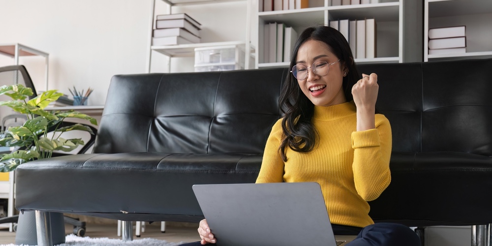 Euphoric Young Asian Woman Celebrating Winning Or Getting Ecommerce Shopping Offer On Computer Lapto