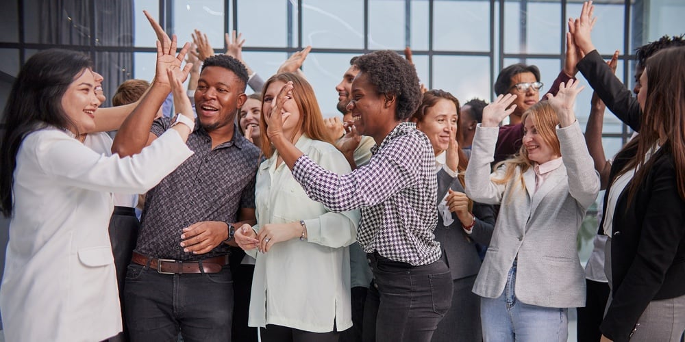 Excited Multinational Employees Celebrating Team Victory Giving High Five Gathered In Office