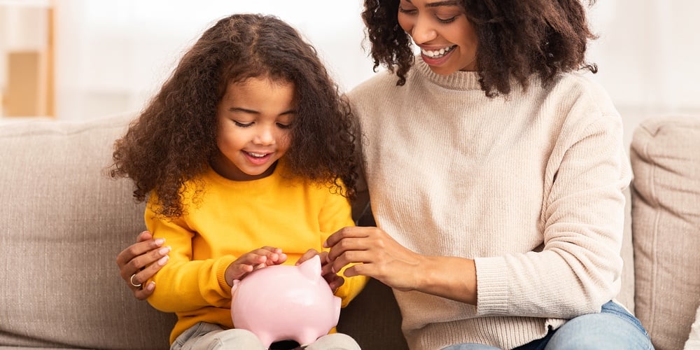 Family Savings. Cheerful Afro Mother Teaching Little Daughter How To Save Money Holding Piggybank Si