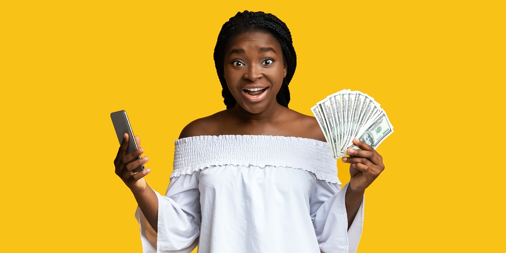 Fast Credits. Excited Black Lady Holding Smartphone And Dollar Cash