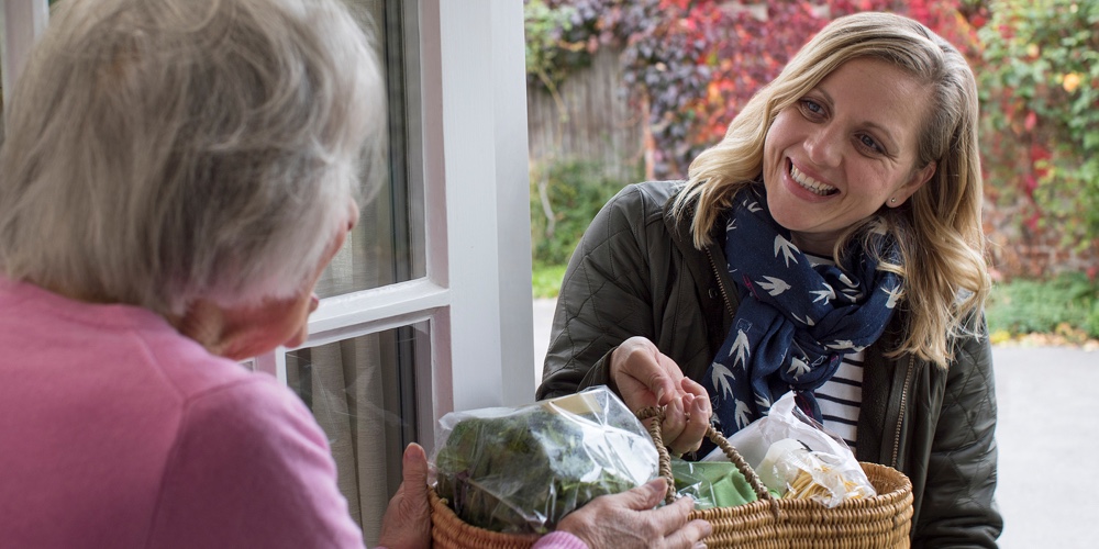 Female Neighbor Helping Senior Woman With Shopping