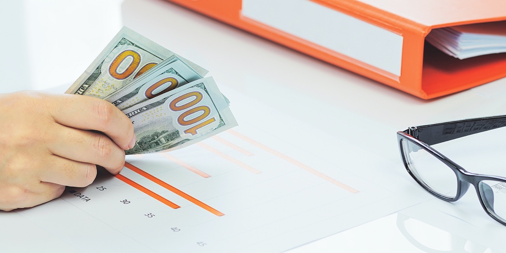 Finance And Business Concept. Small Business Growth. Hand Holding Cash Dollars Stack Over Financial