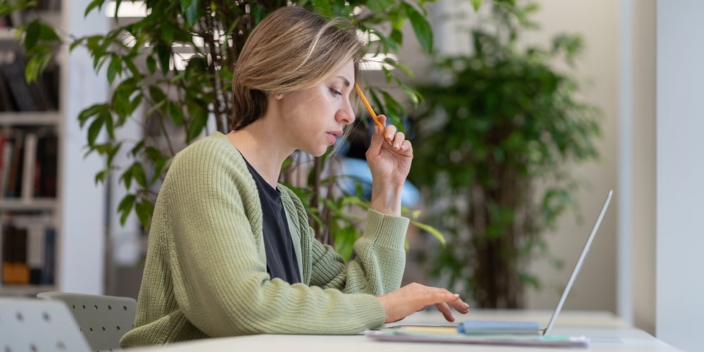 Focused Pensive Woman University Professor Preparing Lecture Material On Laptop In Light Cozy Librar