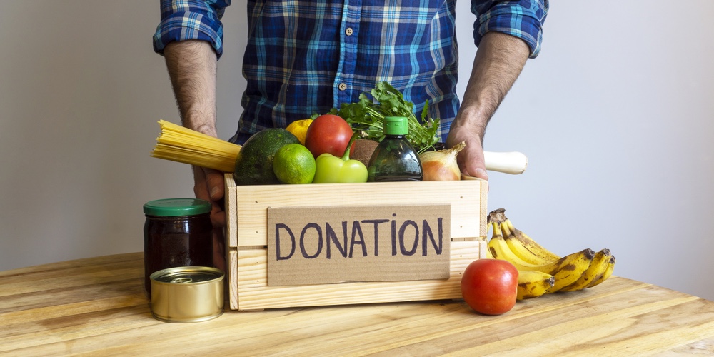 Food Donation Concept. A Man Holding A Donation Box With Vegetables