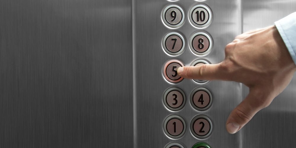 Forefinger pressing the fifth floor button in the elevator