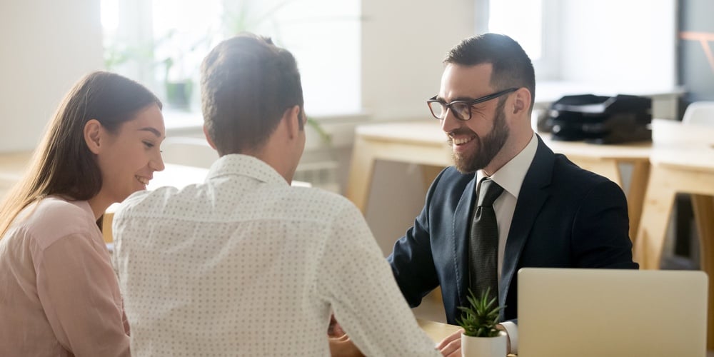 Friendly Lawyer Or Financial Advisor In Suit Consulting Young Couple