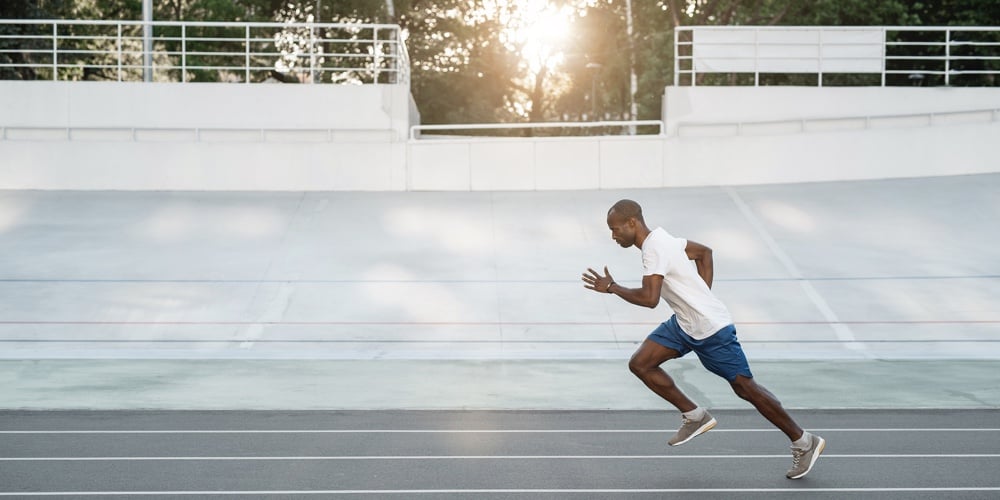 Full Length Side View Focused Male Athlete Gesticulating Hands While Running On Track Field. Copy Sp