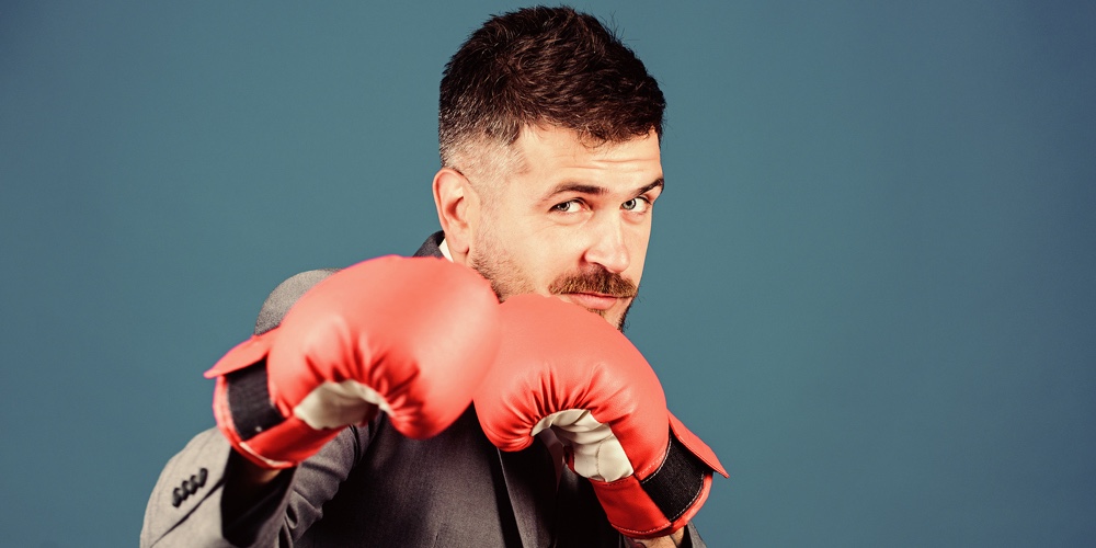 Full Of Energy. Bearded Man In Boxing Gloves Punching. Business And Sport Success. Powerful Man Boxe
