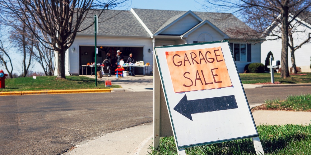 Garage sale sign on the lawn of a suburban home