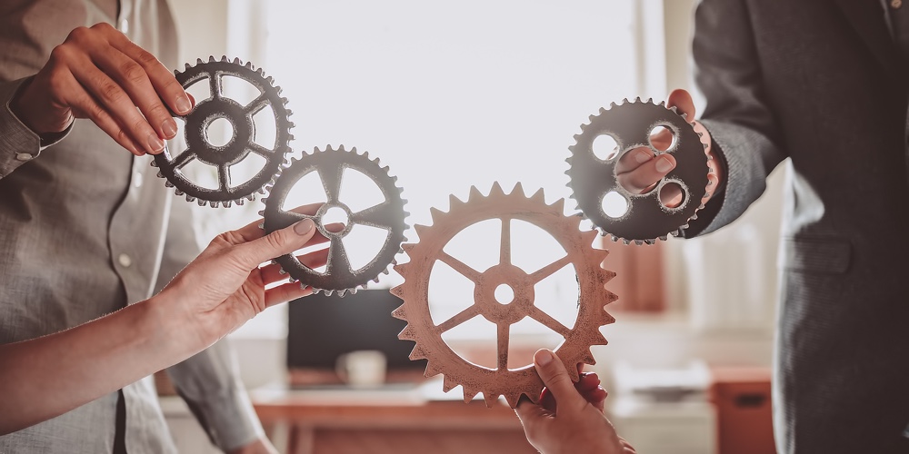 Group Of People Working In The Office While Putting Together Cogwheels. Concept Of Teamwork And Toge