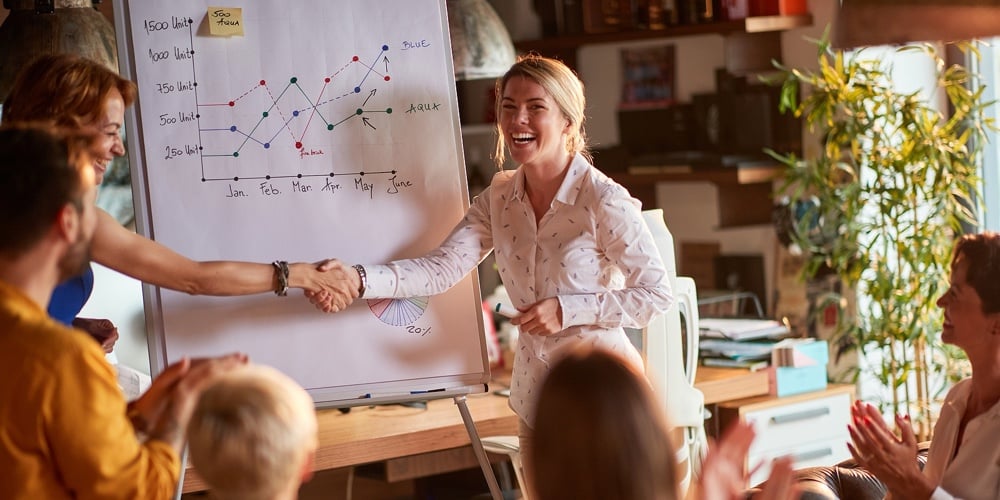 Group of business people congratulate their young female colleague on successful presentation in a p