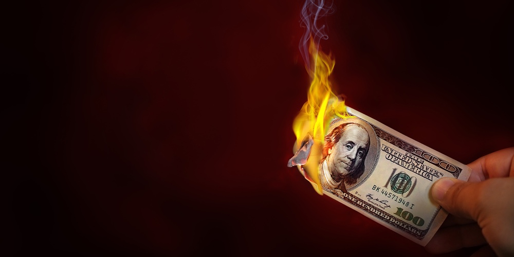 Hand Holding A Burning 100 Dollar Bill Money With Copy Space.