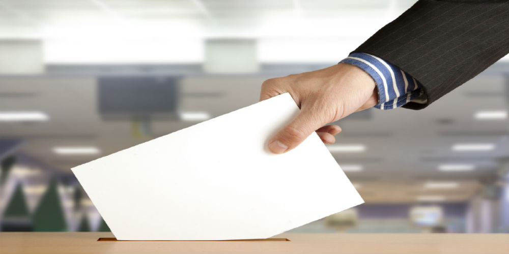 bigstock-Hand-putting-a-voting-ballot-i-31828202