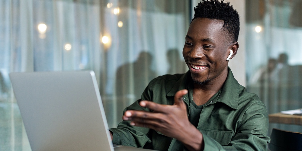 Handsome African American Man Using Computer And Smiling. Online Video Chat With Friends