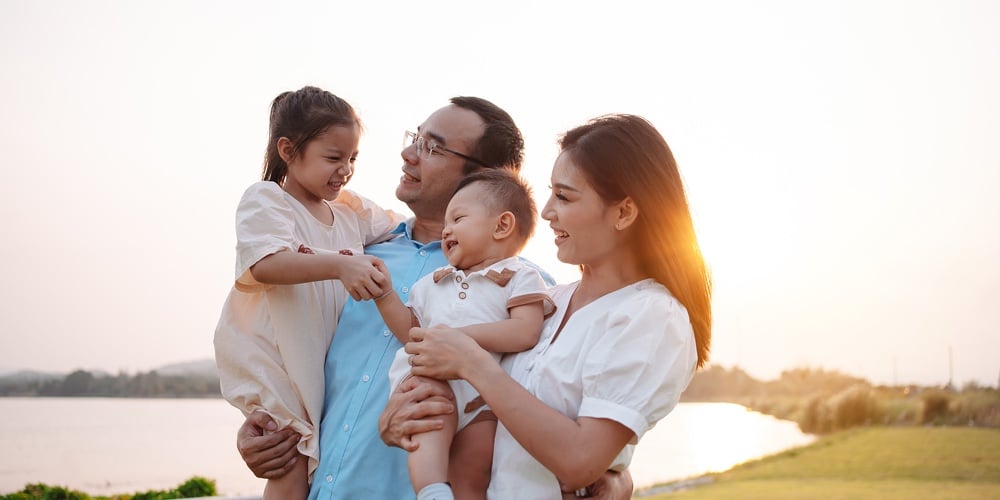 Happy Family In The Park Sunset Light. Family On Weekend Playing Together In The Meadow With River P